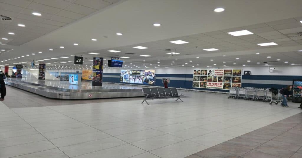 The baggage claim area at Prague Airport with waiting passengers.