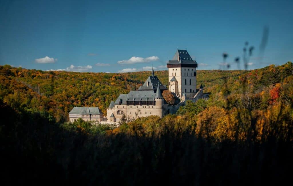 A view of Karlstejn Castle from Prague surrounded by colorful trees