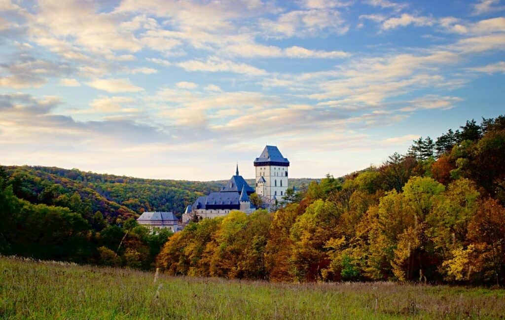 A beautiful view of Karlstejn Castle from Prague surrounded by autumn foliage.